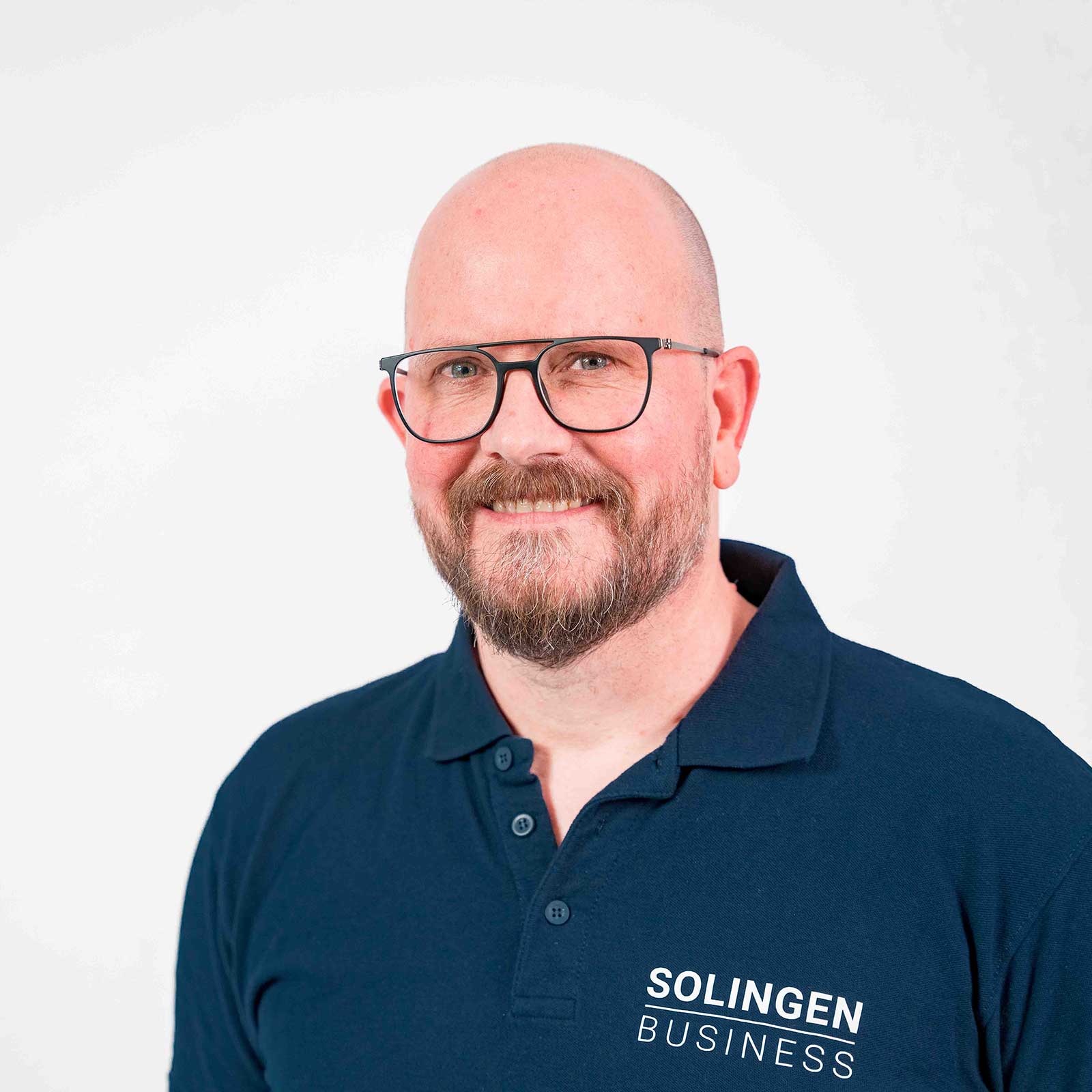 Porträt von Achim Willke Teammitglied von Solingen.Business, in blauem Poloshirt vor hellem Hintergrund