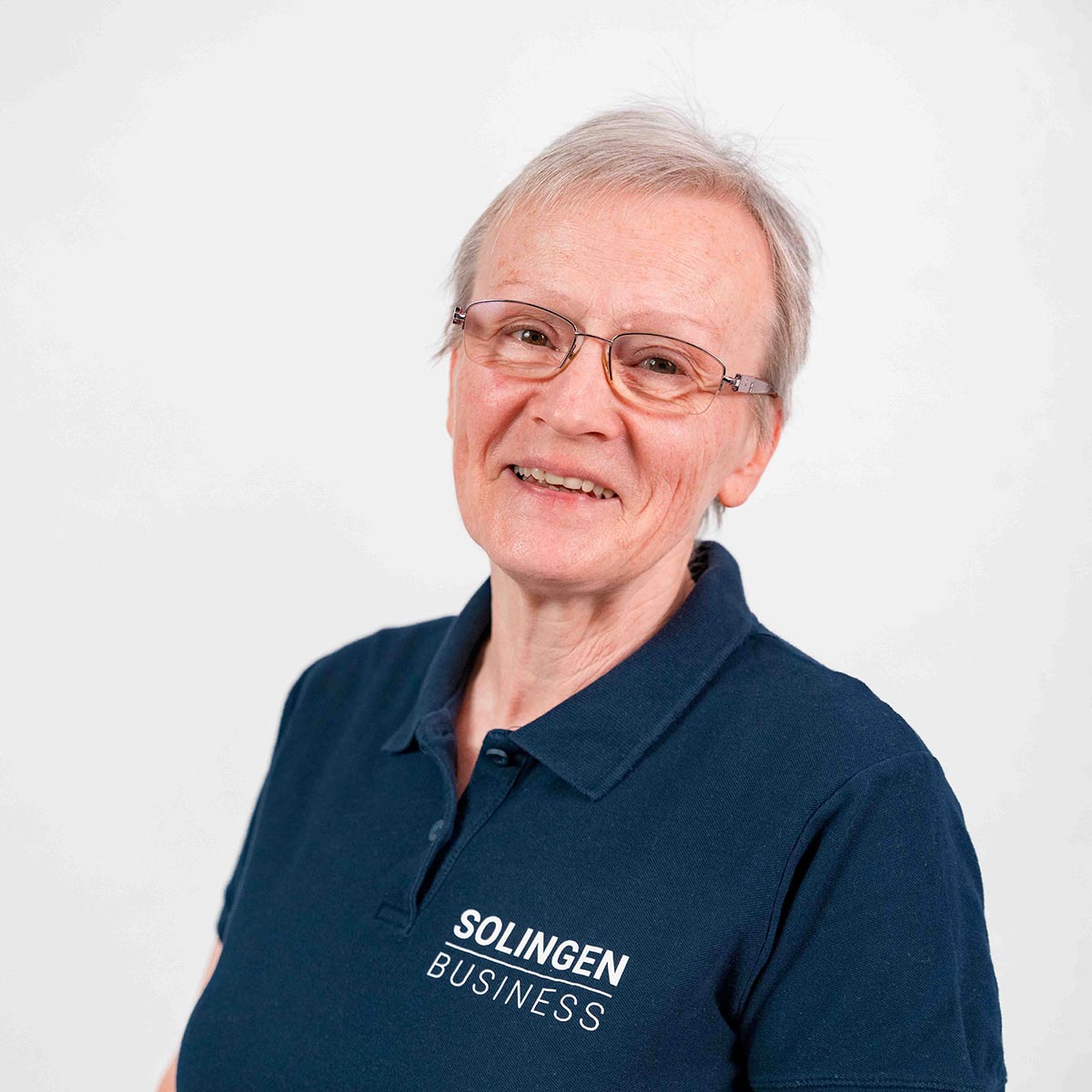 Porträt von Christel Daniel, Teammitglied von Solingen.Business, in blauem Poloshirt vor hellem Hintergrund