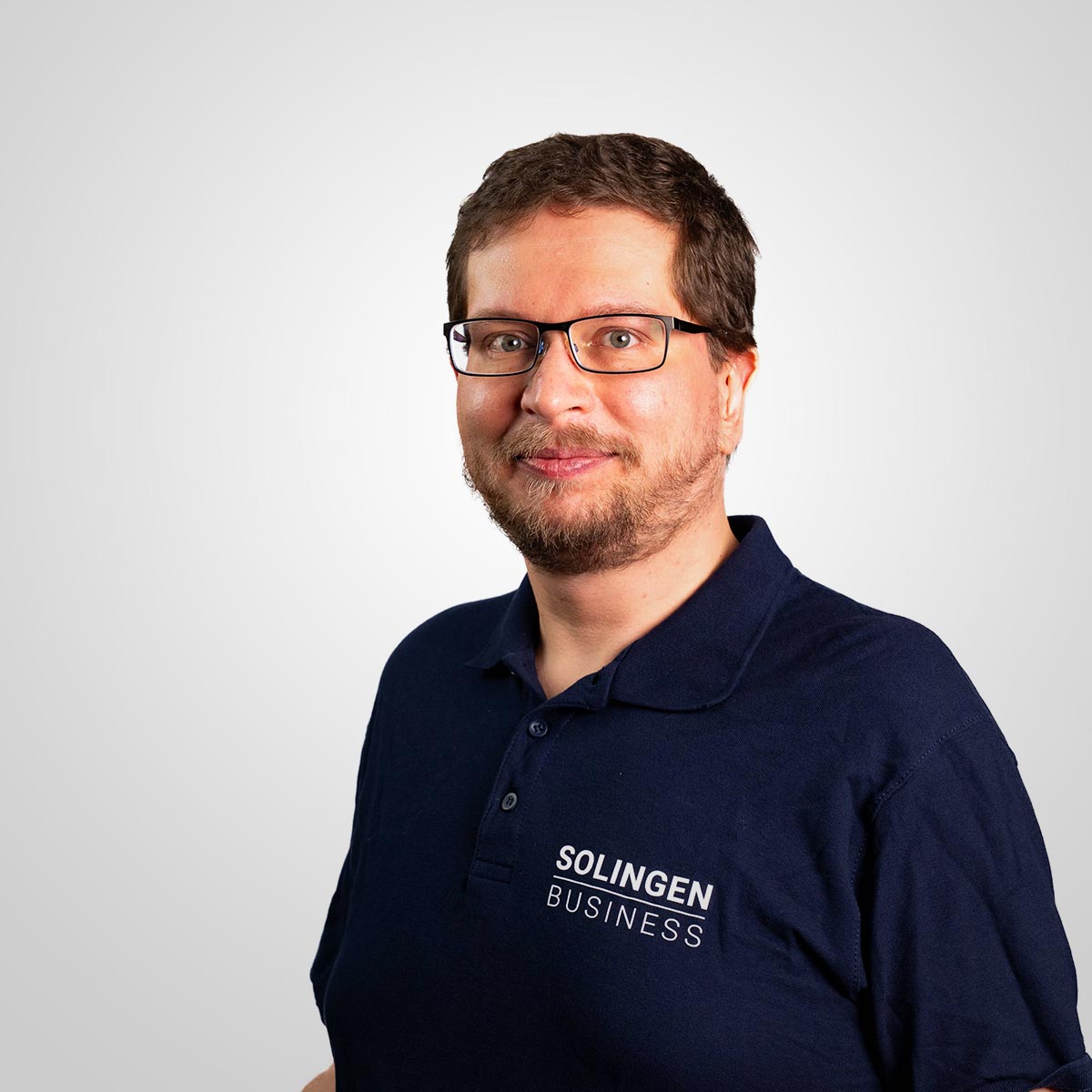 Porträt von Christoph Anderssohn, Teammitglied von Solingen.Business, in blauem Poloshirt vor hellem Hintergrund