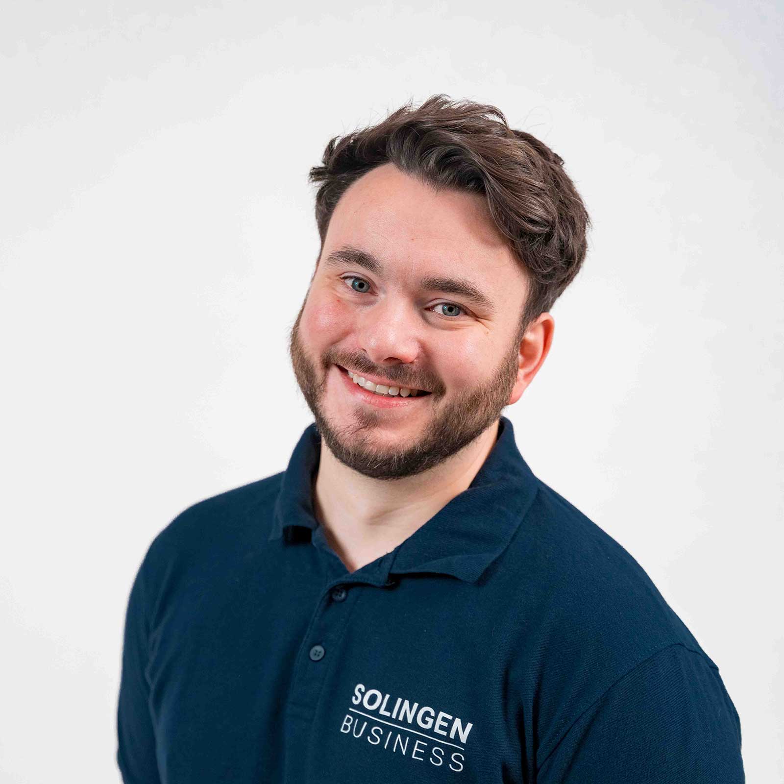 Porträt von Phil Derichs, Teammitglied von Solingen.Business, in blauem Poloshirt vor hellem Hintergrund