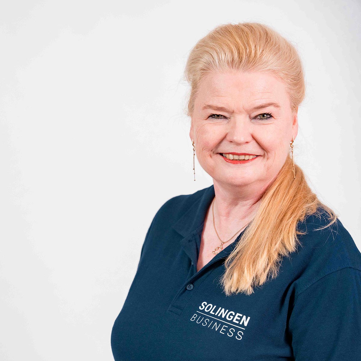 Porträt von Simone Ohliger, Teammitglied von Solingen.Business, in blauem Poloshirt vor hellem Hintergrund