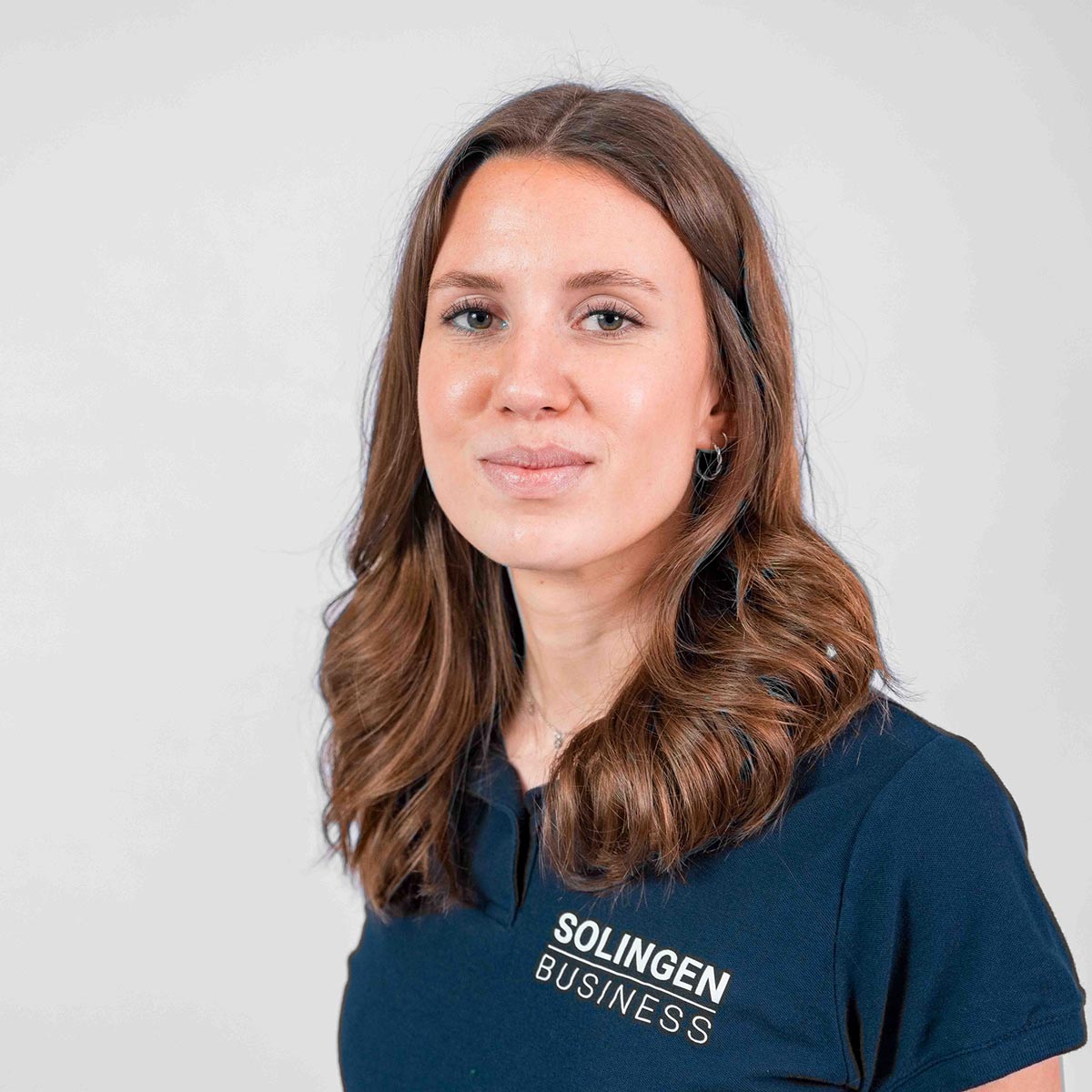 Porträt von Jessica Buschhaus, Teammitglied von Solingen.Business, in blauem Poloshirt vor hellem Hintergrund