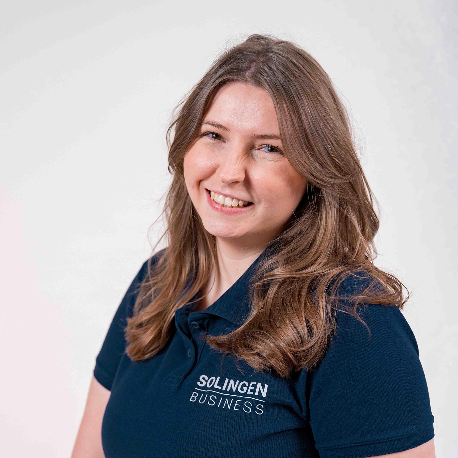 Porträt von Laura-Sophie Voß Teammitglied von Solingen.Business, in blauem Poloshirt vor hellem Hintergrund